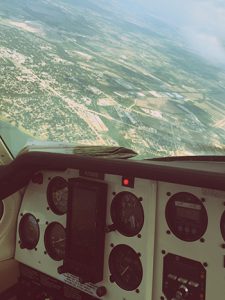 view of a planes dashboard and windshield while flying above a small town