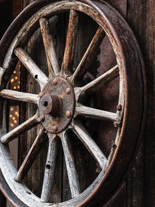a wagon wheel leaning against and old wooden building