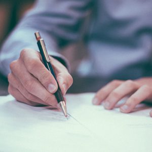 close up of a business man's hands writing with a pen