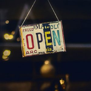 handmade open sign made of old license plate scraps hanging in a window