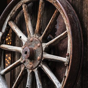 a wagon wheel leaning against and old wooden building