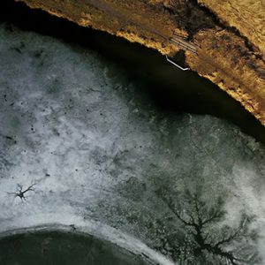 aerial view of a frozen lake and the shore with shack and deck